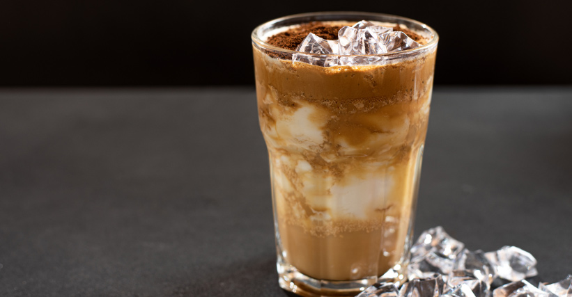 Como fazer café gelado - Copo de vidro com café gelado e cubos de gelo ao lado.