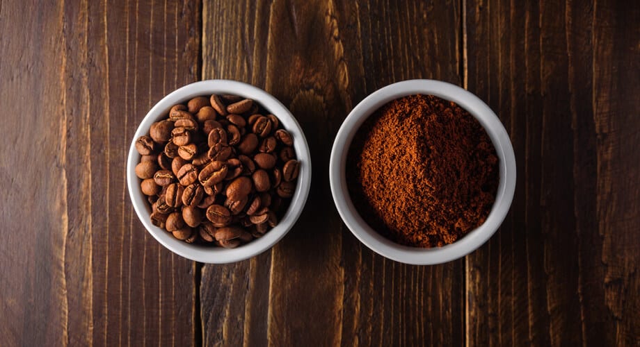tigela com café de moagem fina ao lado de tigela com grãos de café
