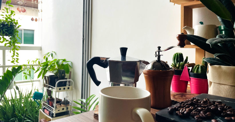 Como fazer um cantinho do café? Cantinho do café em casa, com cafeteira, xícaras e algumas plantas.