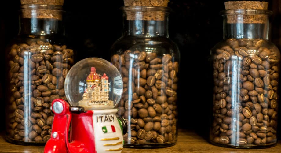 Itens de artesanato com grãos de café: potes com grãos ao fundo e um enfeite da Itália à frente
