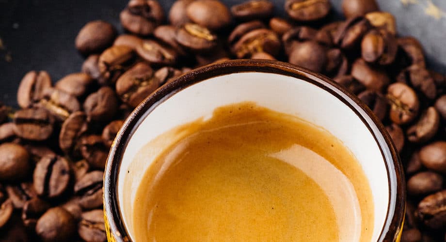 imagem de grãos de café ao lado de uma xícara de café espresso