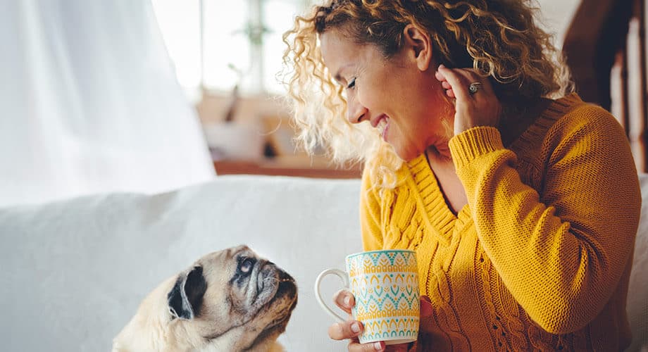 cachorro e sua totura se olhando com uma xícara de café em mãos