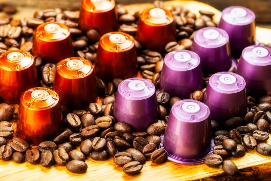 Bandeja de madeira com grãos de café e cápsulas organizados.